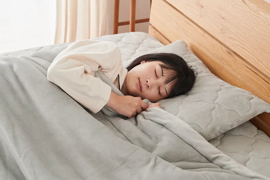 女性が毛布をかぶり寝ている画像